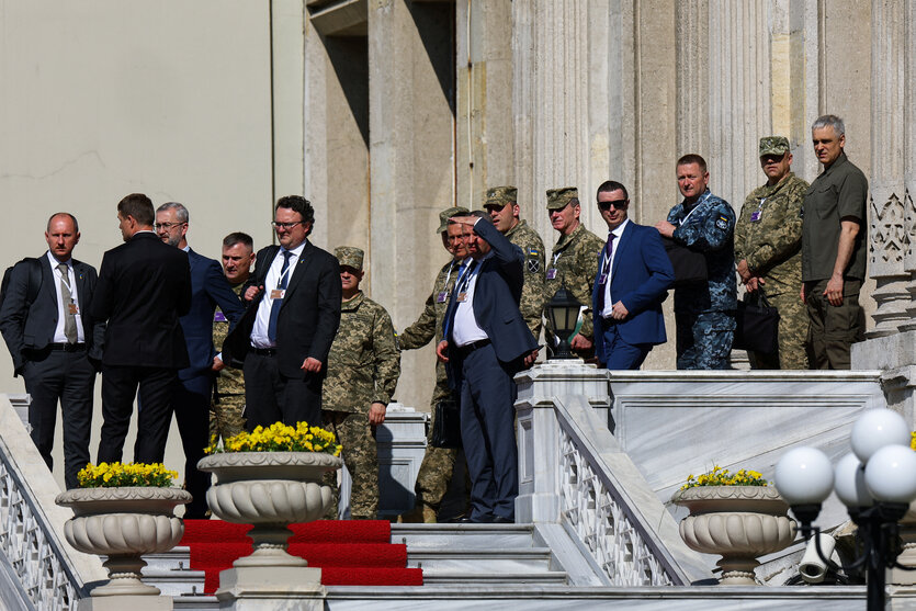 Männer in Uniformen und Anzügen stehen auf einer Treppe