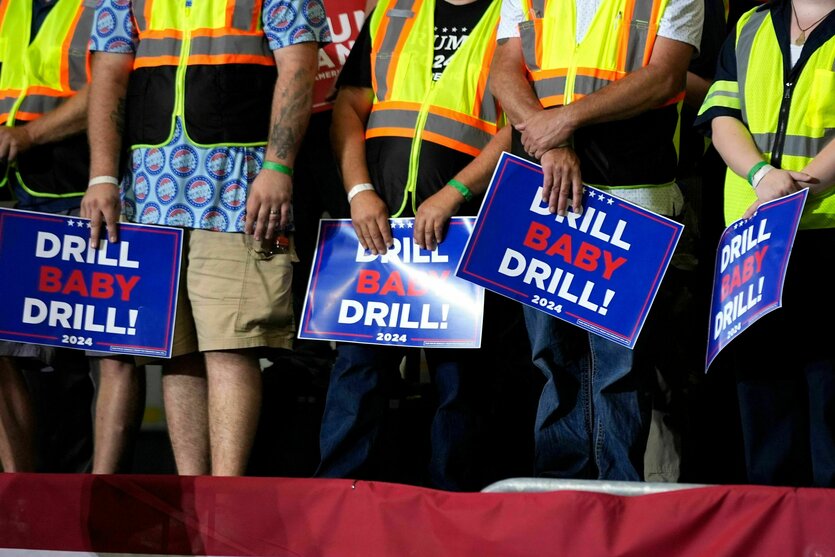 Menschen in Schutzwesten tragen Schilder mit der Aufschrift "Drill Baby Drill"
