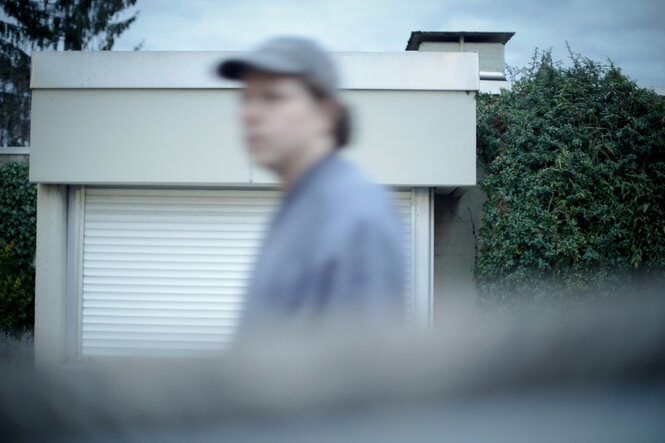 Ein verschwommenes Foto von Julian Knoth vor einer Garage in hellen Blautönen