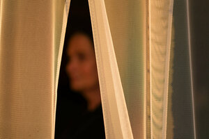 Eine unscharfe Frauengestalt hinter einem Vorhang