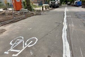 Selbst gemalte Radspur mit Rad-Piktogramm auf einer Straße