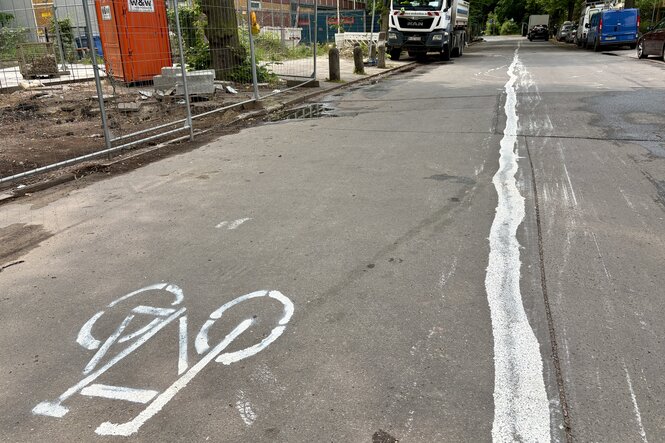 Selbst gemalte Radspur mit Rad-Piktogramm auf einer Straße