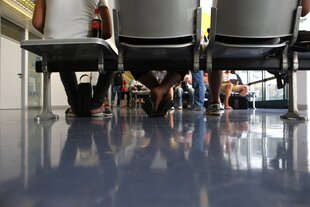 Menschen sitzen auf Stühlen und warten, Kamera in Fußhöhe