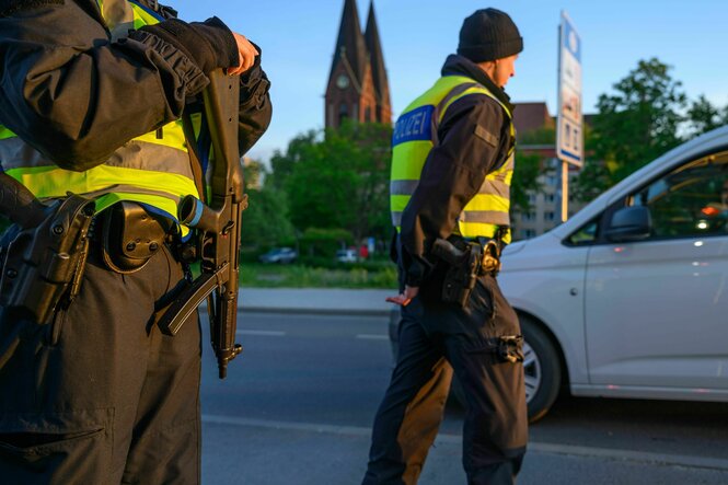 Zwei Beamte der Bundespolizei stehen bewaffnet und in gelben Warnwesten an einer Straße