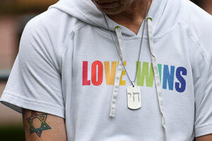 Liebe gewinnt steht in bunten Lettern auf einem Shirt, ein bunter Judenstern ist auf den Arm tätowiert, eine Kette mit dem hebräischen Buchstaben für Leben