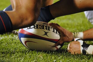 Hände und Beine kämpfen um einen Rugby Ball
