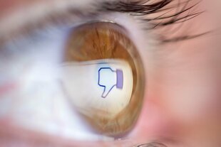 Daumen-runter-Emoji spiegelt sich in einem Auge