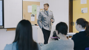 Julian Ströbl steht in Uniform in einem Klassenzimmer