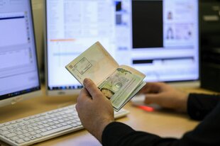 Ein Pass und Bildschirme in einer Behörde.