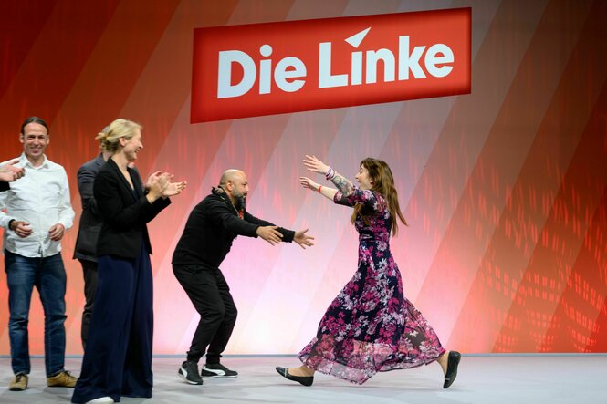 Heidi Reichinnek rennt auf Ferat Kocac auf einer Bühne zu