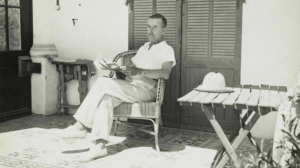 Thomas Mann sitzt in einem Korbsessel im Schatten vor einem Haus in Südfrankreich