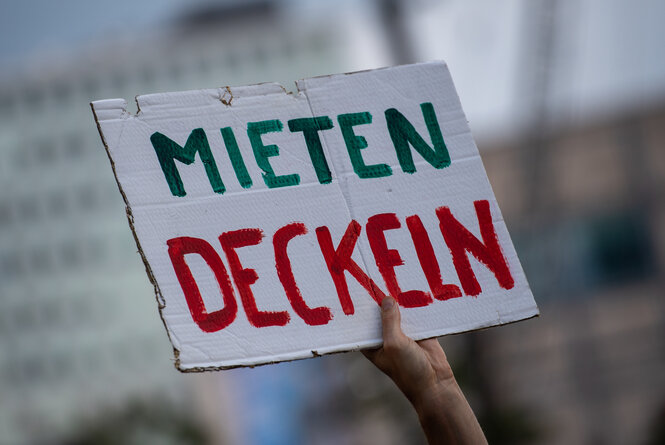 Auf einem Pappschild steht "Mieten deckeln"