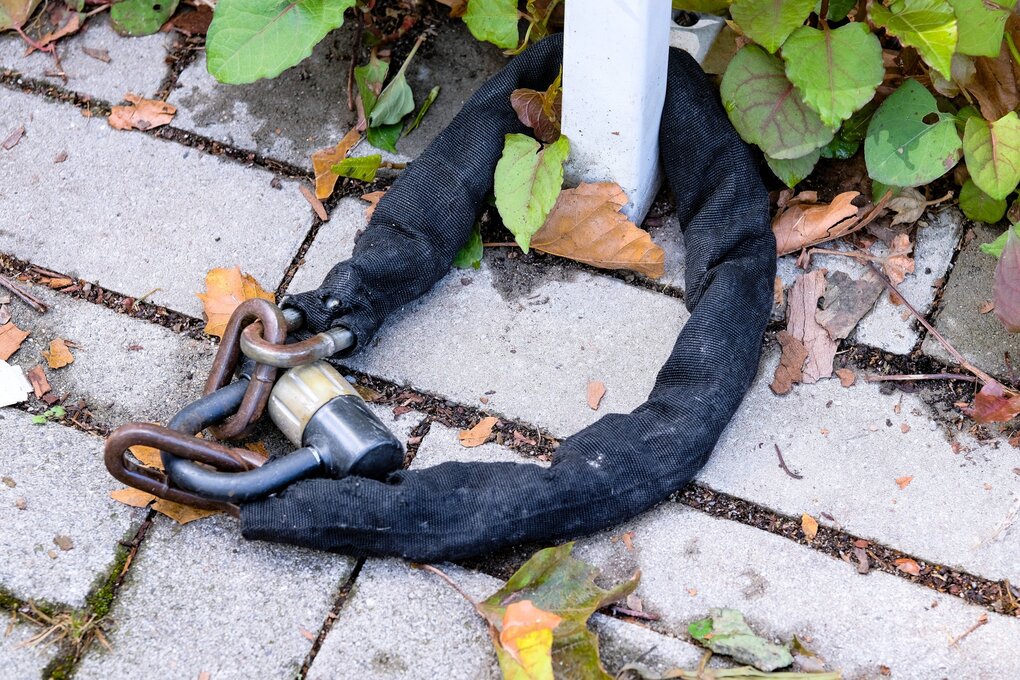 EIn dickes Fahrschloss liegt auf dem Boden an einen Pfosten gekettet