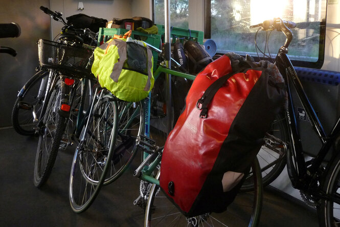 Fahrräder mit Gepäcktaschen stehen in einer Regionalbahn im Fahrradabteil