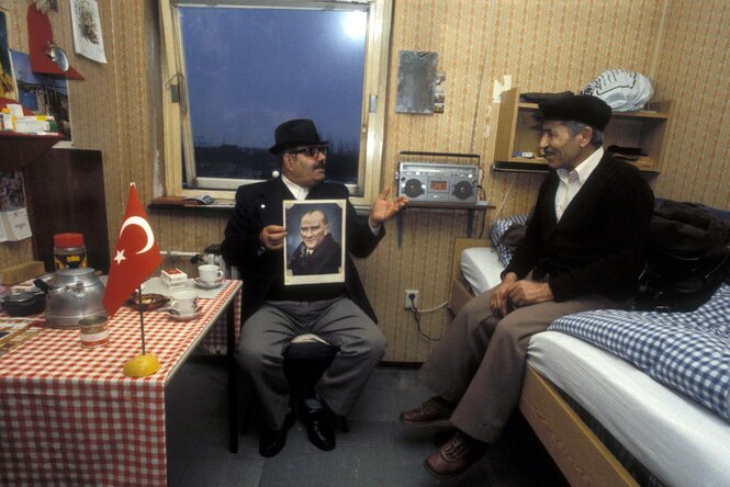 Türkischer Gastarbeiter mit einem Bild von Atatürk und Besuch von einem Kollegen in seiner Wohnung in Rüsselsheim, im Hintergrund ein Radio