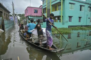 Aufgrund starker Regenfälle ist ein Fluss über die Ufer getreten. Boote sind das einzige Transportmittel für die Menschen, selbst auf den Straßen der Wohngebiete