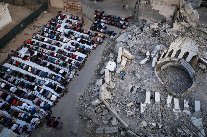 Menschen beten neben einer zerstörten Moschee