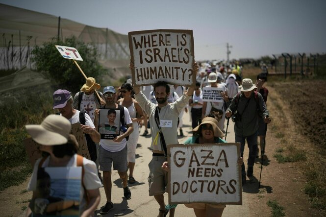 Friedensaktivisten an der Grenze zu Gaza halten Schilder in die Höhe: "GAZA NEEDS DOCTORS" und WHERE IS ISRAELS HUMANITY?"y ?