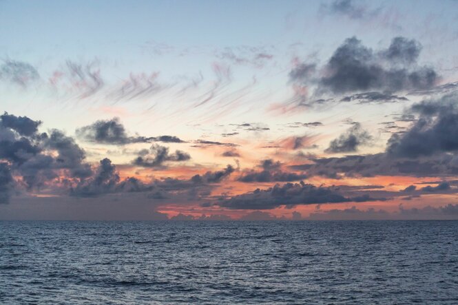 Graue Wolken vor Sonnenuntergang über einem Ozean.