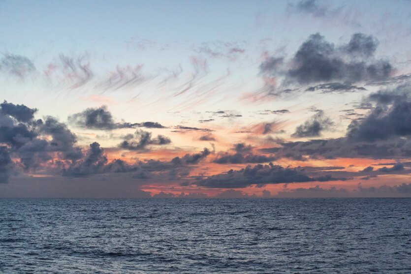 Graue Wolken vor Sonnenuntergang über einem Ozean.