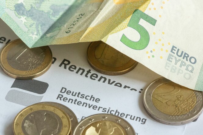 Münzen und eine Banknote liegen auf einer Renteninformation der Deutschen Rentenversicherung