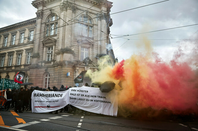 Demonstranten ziehen mit Banner und Bengalos eine Straße entlang