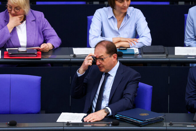 CSU-Innenminister Alexander Dobrindt sitzt im Bundestag und kratzt sich den Kopf.