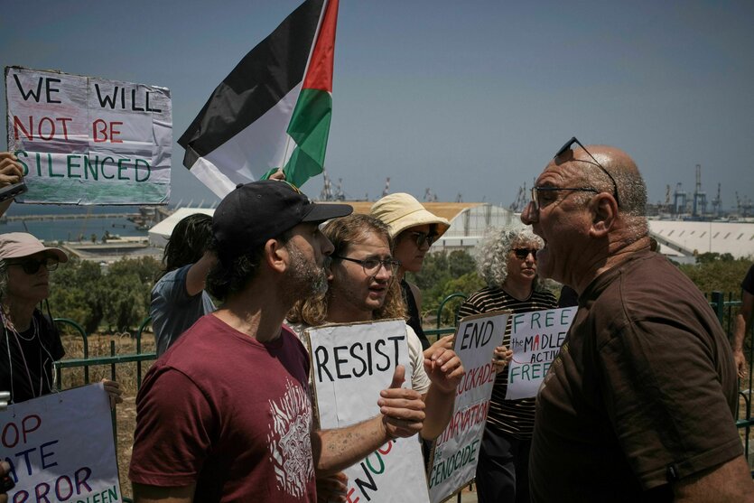 EIn Mann schreit Demonstranten an, die Schilder wie "Resist" und eine Palästina-Fahne bei sich tragen