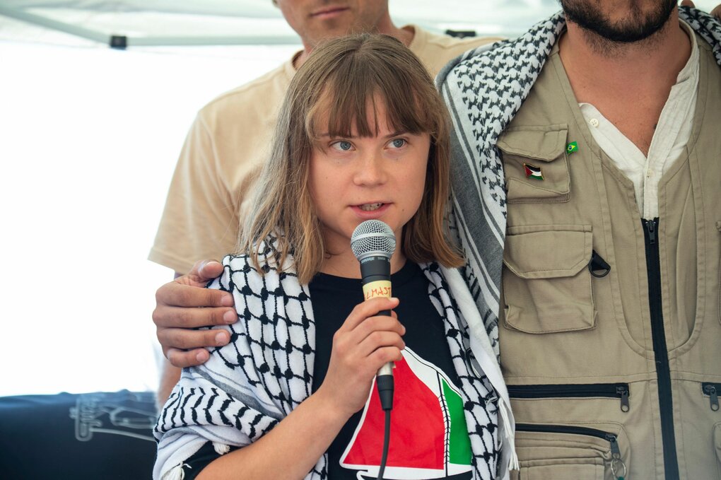 Greta Thunberg mit Palästinensertuch und Mikrofon in der Hand, ein Mitstreiter legt einen Arm um sie
