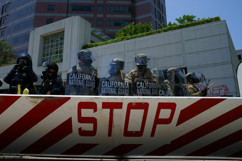 Absperrung mit „Stop“-Aufschrift vor Bürogebäude, gepanzerte Soldaten mit Gasmasken und Schilden mit der Aufschrift „California National Guard“