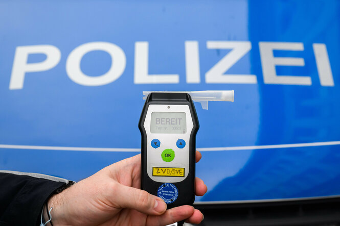 Ein Polizist hält ein Gerät für einen Alkoholtest in der Hand.