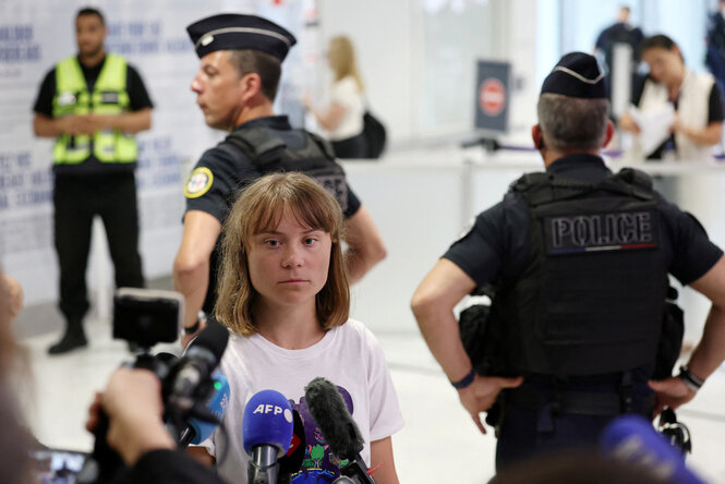 Eine junge Frau spricht mit Vertretern der Presse, während Polizisten die Situation bewachen
