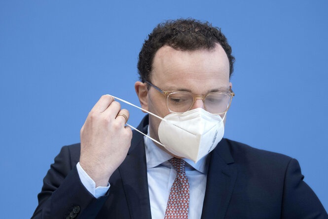 Ein Mann mit Brille setzt sich eine FFP-2-Maske auf