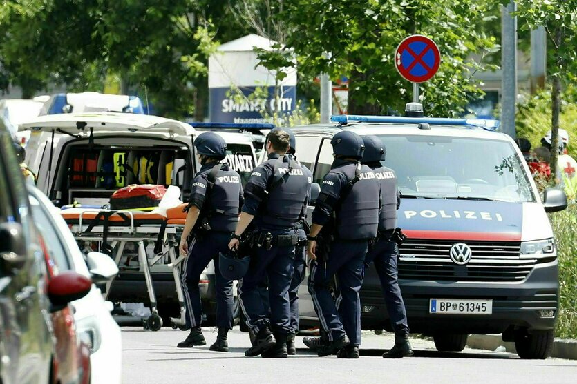 Einsatzkräfte der Polizei stehen in der Nähe des Tatorts an einer Grazer Schule