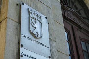 Ein Schild an einem Gebäude, darauf steht Verfassungsgerichtshof, daneben das Berliner Wappen