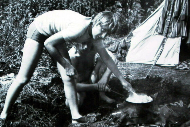 Angela Merkel bückt sich im Juli 1973 auf einem Campingplatz zu einer Feuerstelle.