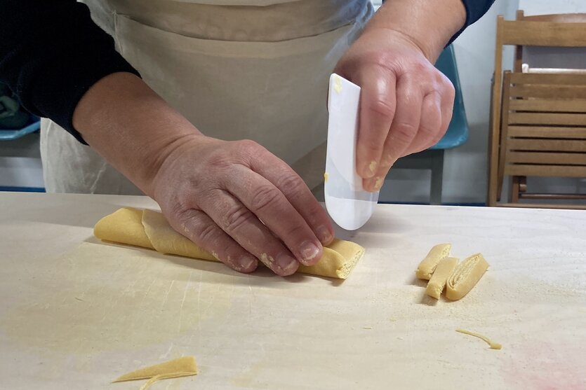Eine Person stellt Pasta her.