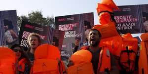 Aktivisten demonstrieren mit Rettungswesten und Plakaten
