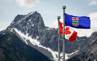 Eine kanadische Flagge (l) und eine Flagge von Alberta flattern im Wind, im Hintergrund der Wedge Mountain am Ort des G7-Gipfels der Staats- und Regierungschefs