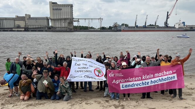 Teilnehmende des Wesercamps protestieren am Strand von Harriersand vor der Industriekulisse gegen Palmöl