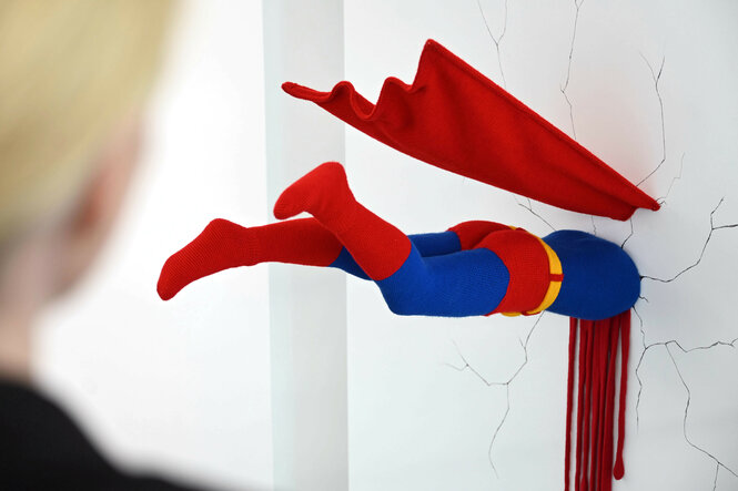 Das Werk „O.T. (Superman)” von Patricia Waller. Zu sehen ist eine Superman-Skulptur, die in einer Wand steckt und dabei blutet.