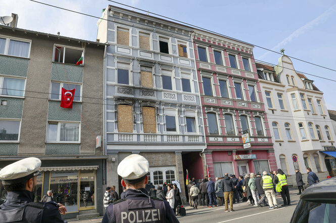 Gedenkstunde, ein Jahr nach dem Brandanschlag auf der Gruenewalder Strasse mit der türkischen-islamischen Gemeinde Ditib vor dem Haus stehen Mahnwachen mit den Namen und Bildern der ums Leben gekommenen Familie Zhilova und ein Tisch mit Blumen, Grablampen und Stofftieren, die Trauerfeier wird von der Polizei beobachtet.