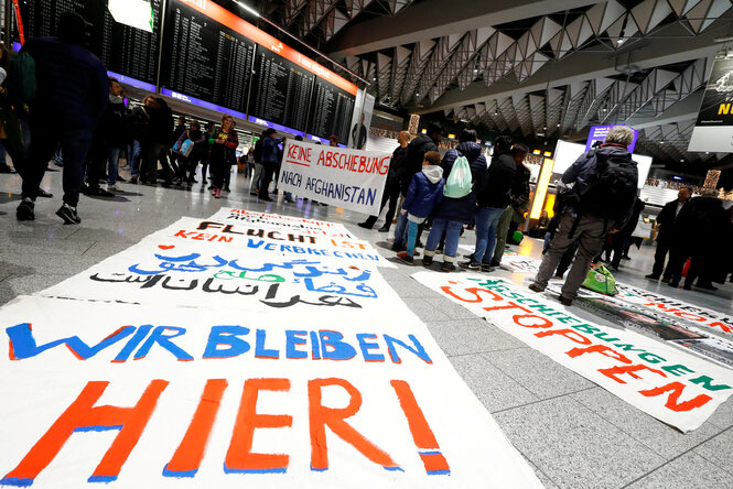 Protestierende zeigen am Frankfurter Flughafen Transaprente mit der Aufschrift "Wie bleiben hier" und "Keine Abschiebung nach Afghanistan"