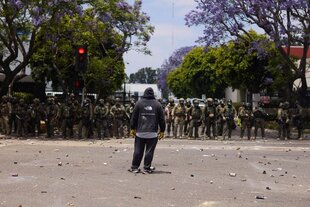 Zu sehen ist ein Demonstrant in den USA, der vor einer Reihe von Spezialsoldaten steht.