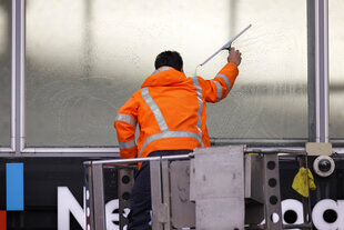 Ein Fensterputzer reinigt auf einer Hebebühne die Scheiben der Eingangshalle des Kölner Hauptbahnhofs