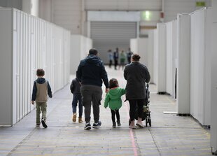 Eine Flüchtlingsfamilie geht durch die zu einer Massenunterkunft umfunktionierten