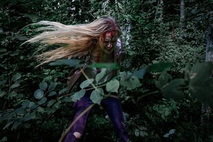 eine junge Frau mit wehenden Haaren ist in einem Wald