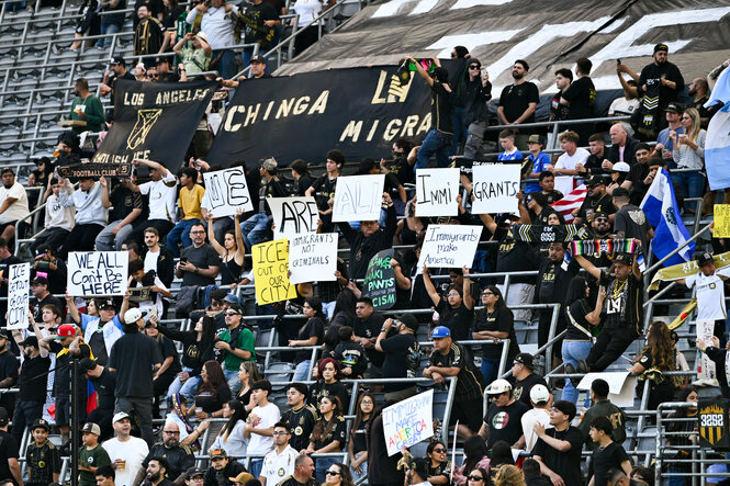 Zuschauer im Stadion heben Protestplakate hoch