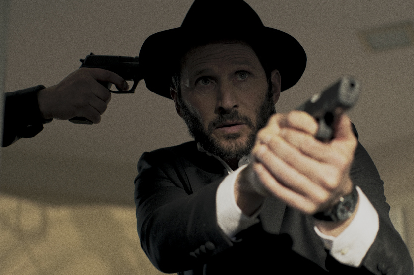 Filmszene: Ein Rabbi zielt mit einer Pistole