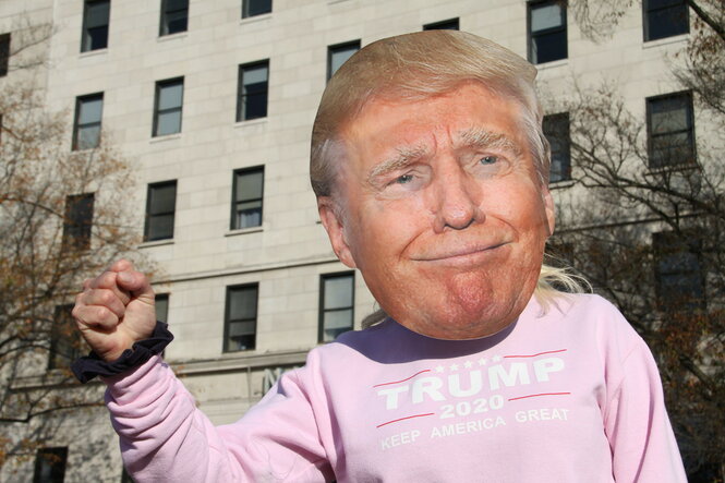 Jemand posiert in einem rosa Sweatshirt mit Trump-Maske